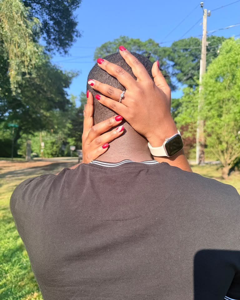 Gamu's hands on Prince's head, her engagement ring showing